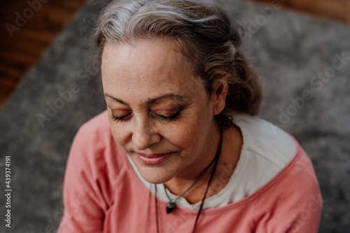 Portrait of serene and happy senior woman relaxing on the floor at home photo