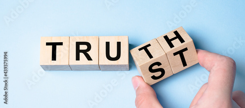 Truth instead of trust. Hand turns dice and changes the word Trust to Truth. photo