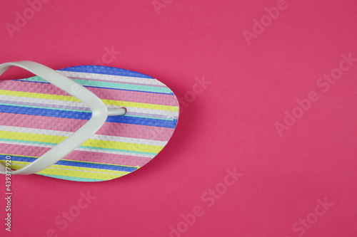 Top view on isolated colorful striped pair flip flops on pink background with copy space