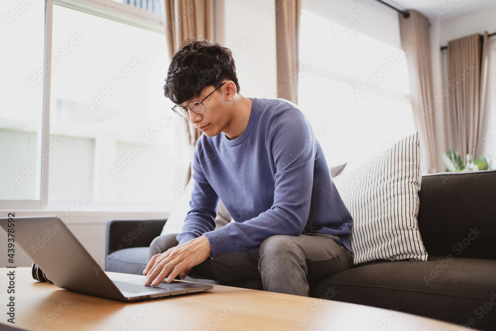 Young attractive man sitting on cozy sofa using laptop at home. Young attractive man sitting on cozy sofa using laptop at home.