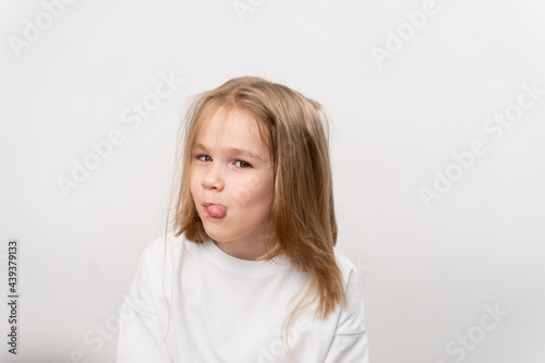 funny girl shows tongue on white background