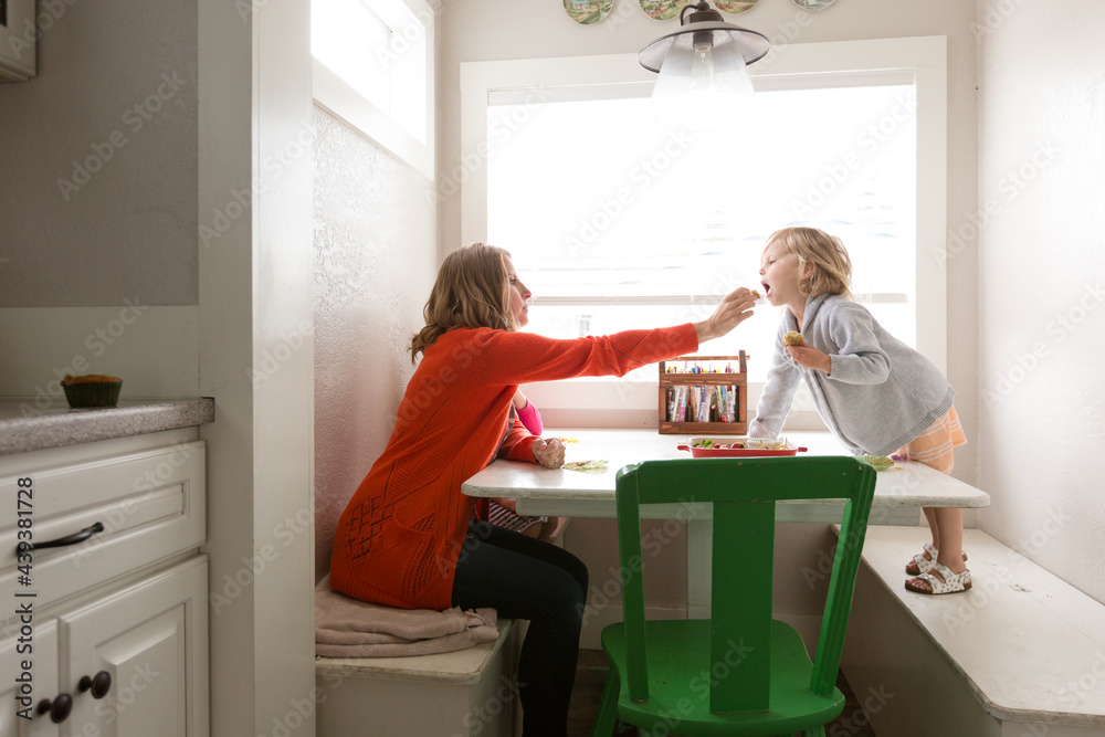 © Jennifer Bogle/Stocksy - Mother offers daughter bite of muffin © Jennifer Bogle/Stocksy - Mother offers daughter bite of muffin