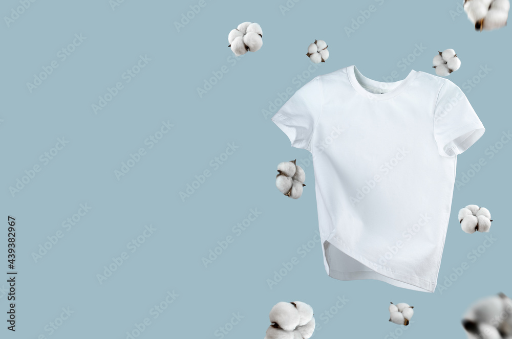 White flying cotton T-shirt isolated on blue background. Clean white t-shirt  for women or men. Unisex. cotton flowers. Branding clothes front view. Mock  up for your design. Classic White Basic T-shirt Stock