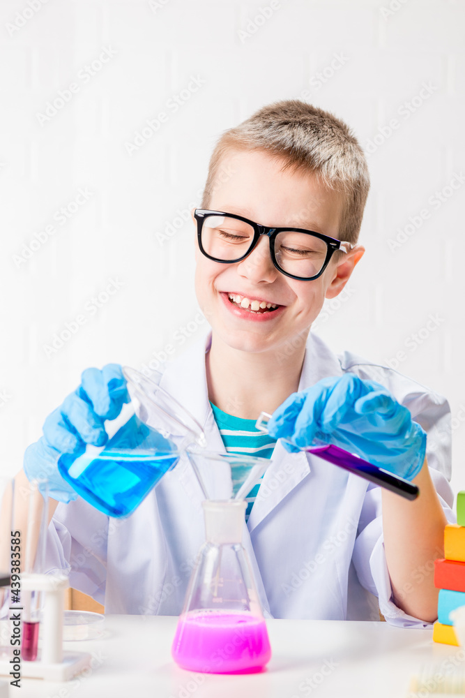 A schoolboy studies multi-colored substances in test tubes, conducts experiments - a portrait on a white background. Concept for the study of coronavirus in the laboratory A schoolboy studies multi-colored substances in test tubes, conducts experiments - a portrait on a white background. Concept for the study of coronavirus in the laboratory