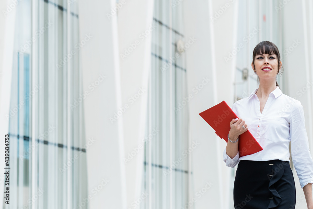 Portrait of beautiful business woman holding notebook on her way to work on city street Portrait of beautiful business woman holding notebook on her way to work on city street