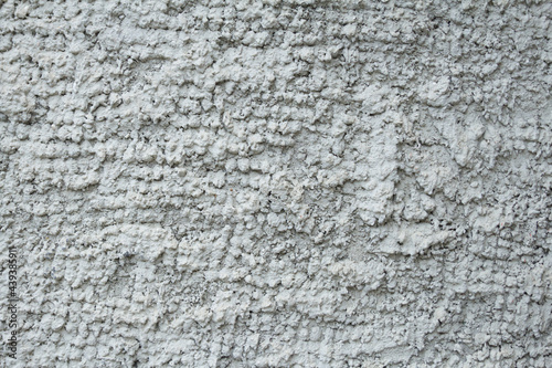 The wall is evenly covered with gray volumetric abstract rough plaster. Background  texture.