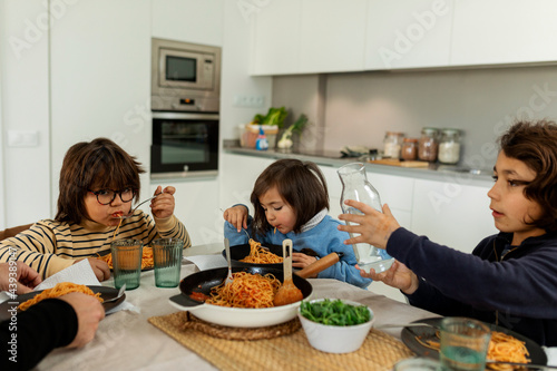 little girl eating pasta at home photo