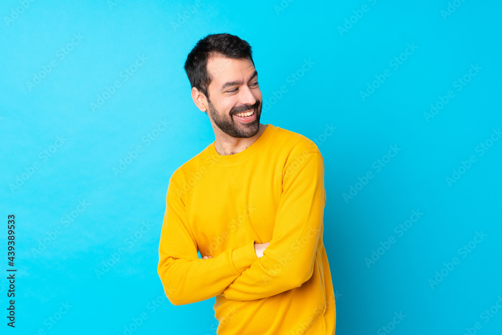 Young caucasian man over isolated blue background with arms crossed and happy Young caucasian man over isolated blue background with arms crossed and happy