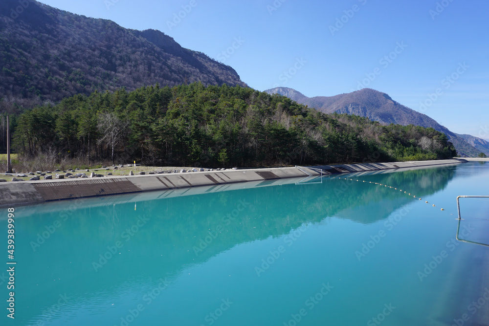 canal of Sisteron, France with mirror reflection of the mountains and trees in the water in the Alps, France canal of Sisteron, France with mirror reflection of the mountains and trees in the water in the Alps, France