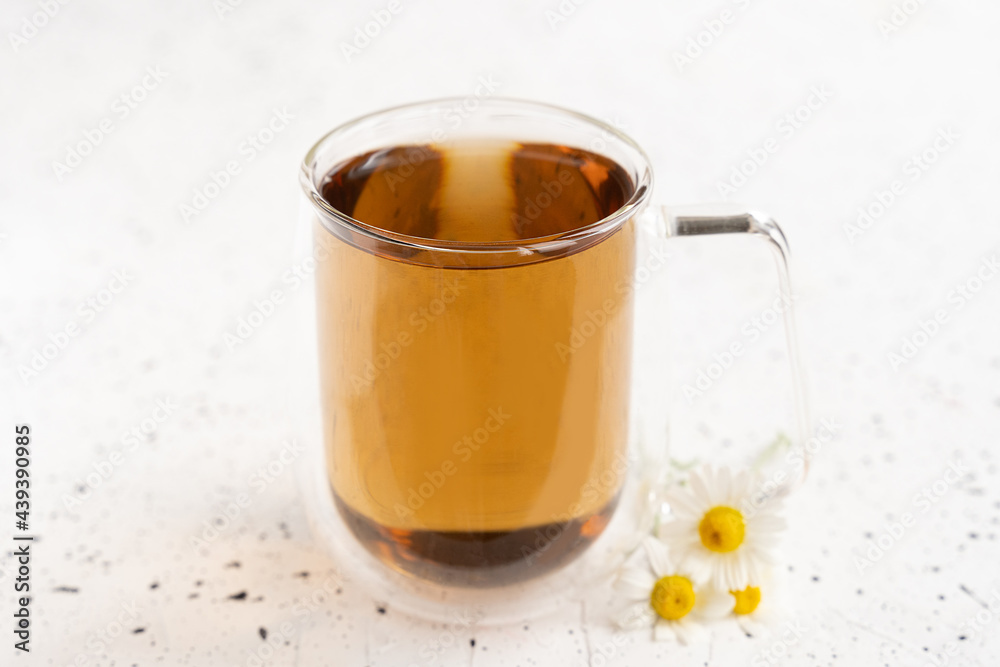 Chamomile tea and chamomile in glass mug on white cement table. Herbal tea. Top view. Flat lay Chamomile tea and chamomile in glass mug on white cement table. Herbal tea. Top view. Flat lay