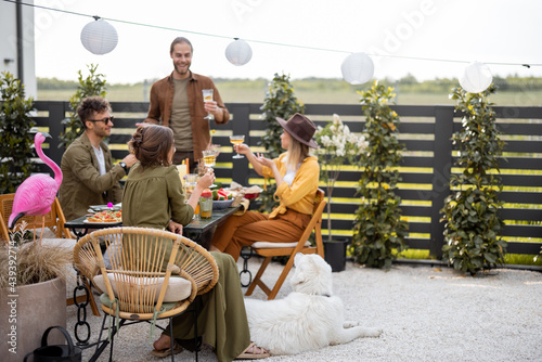 A group of young friends have delicious dinner, toasting and having great summertime together at the backyard of the country house
