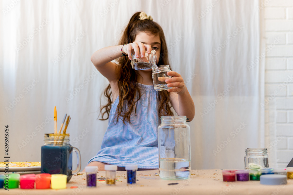 Little girl putting water to make a craft Little girl putting water to make a craft