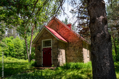An old schoolhouse from the late 1800s sits unused in a forest on a beautiful sunny day in Muskoka, Ontario.