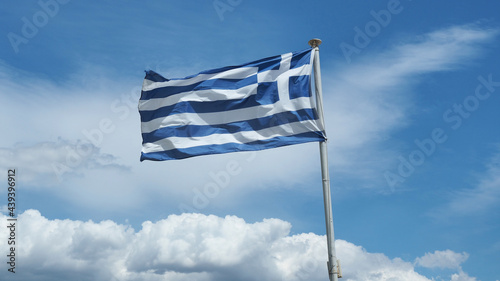 Beautiful white and blue stripes of waving Greek flag on a pole as seen on beautiful deep blue cloudscape