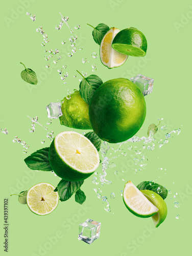 Obraz na płótnie Slices of fresh and ripe lime with ice cubes, splashing water and mint leaves thrown in the air, flying and levitating on a bright green background