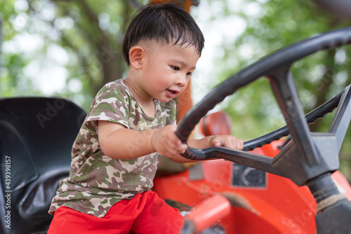 Little boy asian enjoying sitting on a tractor © background photo