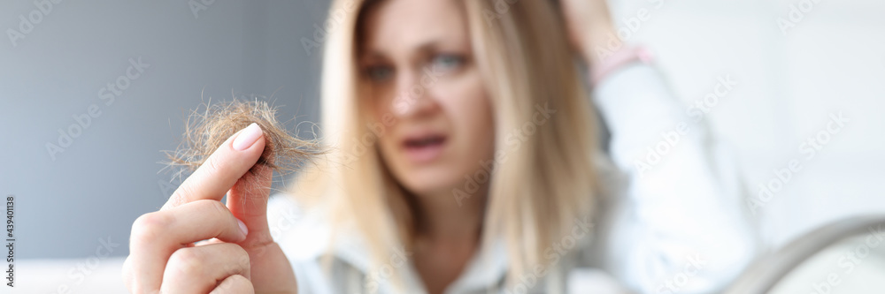 Frustrated woman holds bun of her hair in her hand Frustrated woman holds bun of her hair in her hand