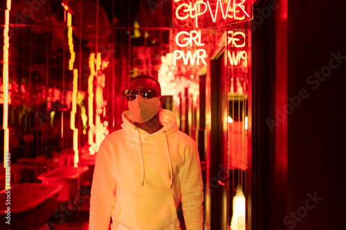Stylish black man under neon signboard in city photo