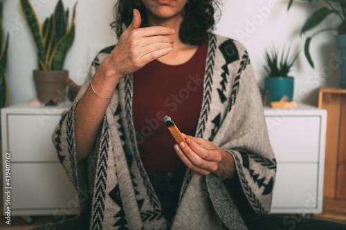 woman meditating with a palo santo dressed with a handmade poncho.background with copy space. concept meditation. horizontal image