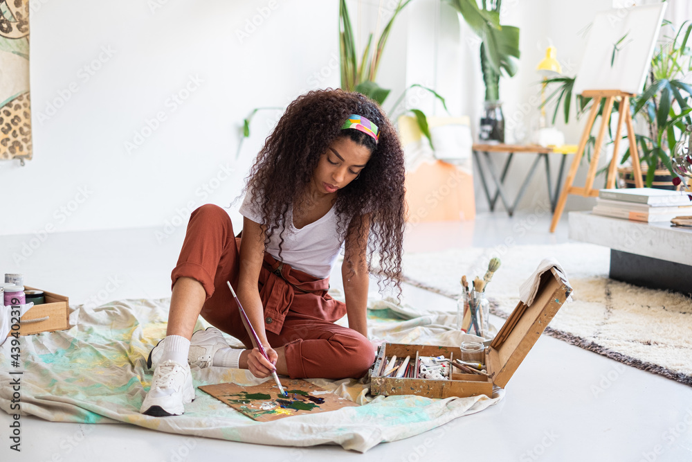 Mixed race artist woman mixing colors in a painter palette StockFoto