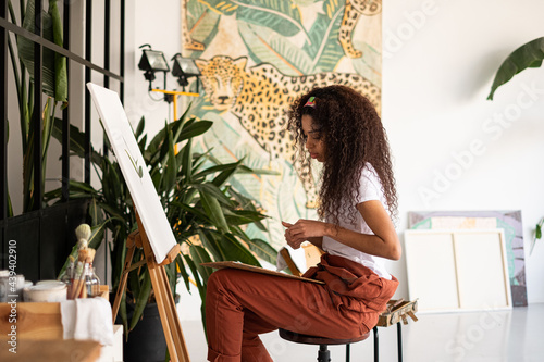 Mixed race Woman painting a picture at her studio. photo