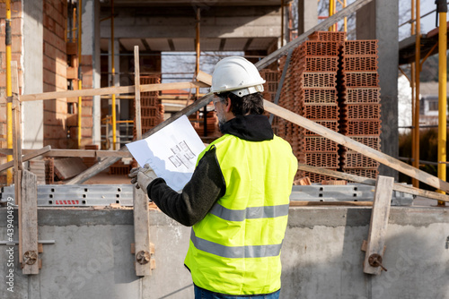 Engineer with blueprint inspecting construction site