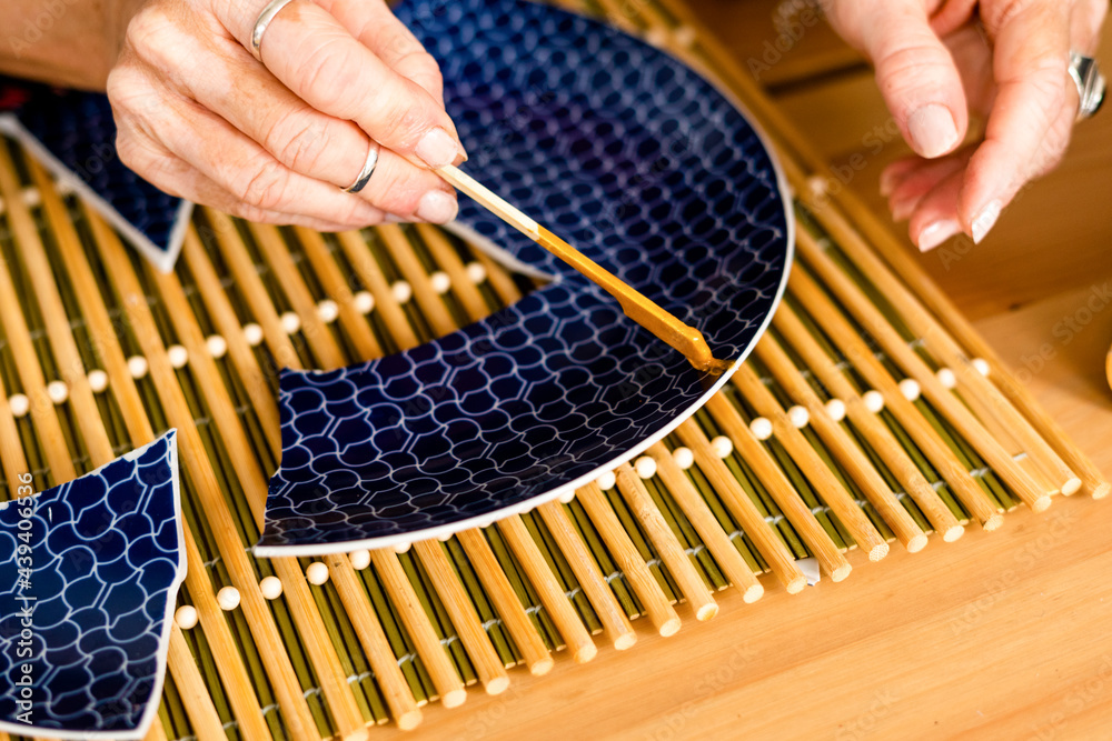 Top view of woman repairing a broken plate with gold Photos Adobe Stock