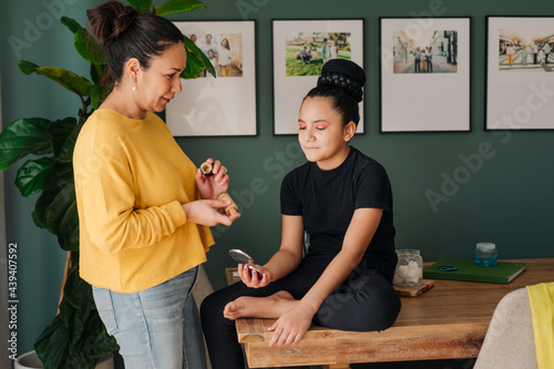Pre-teen girl looking at mirror to check on makeup mother applied
