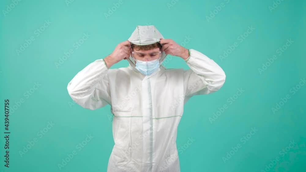 Close up of a man that is wearing protective suit, medical mask and goggles, looking at camera. Isolated on turquoise studio background. Close up of a man that is wearing protective suit, medical mask and goggles, looking at camera. Isolated on turquoise studio background.