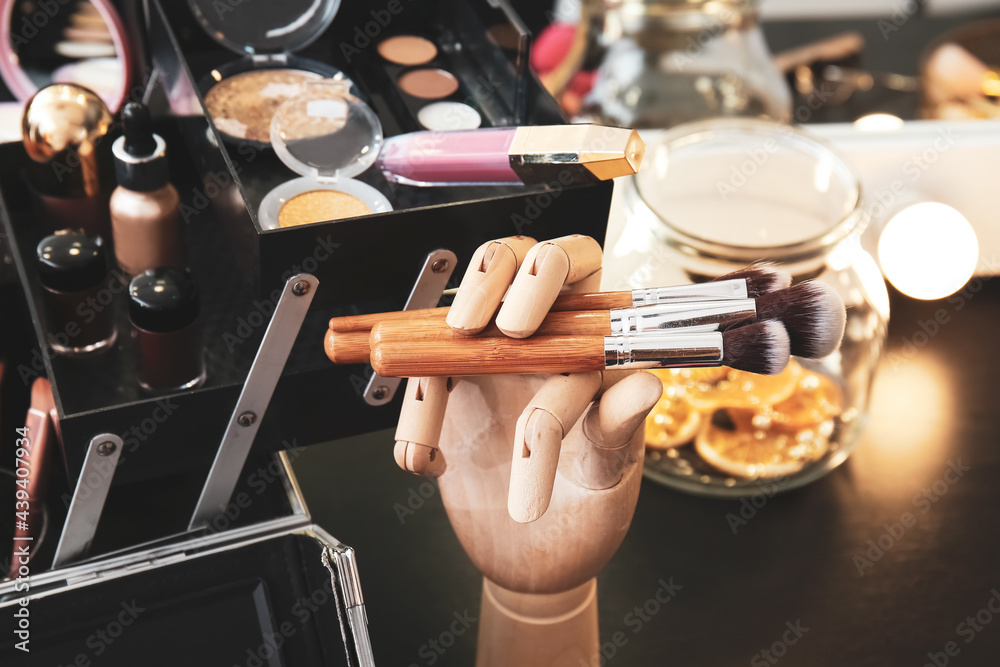Wooden hand with makeup brushes on dressing table, closeup Wooden hand with makeup brushes on dressing table, closeup