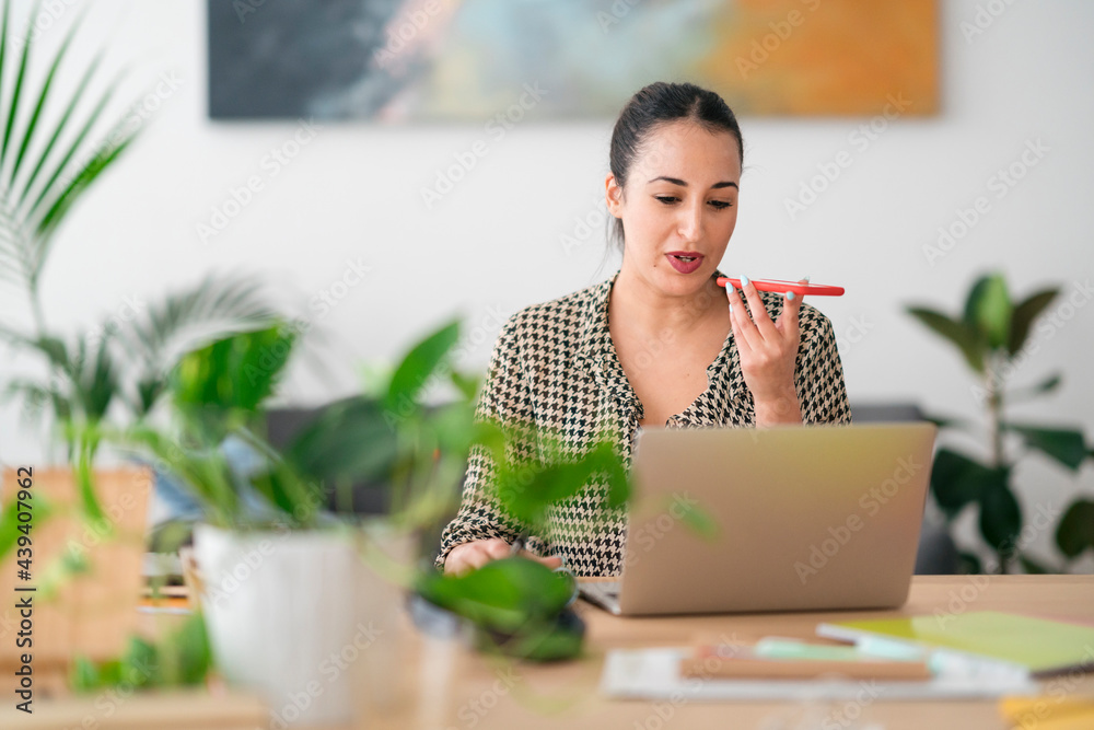 © Studio Marmellata/Stocksy - Focused young Arab woman having phone call and using laptop in workspace
