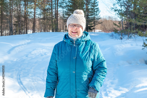 Grandmother walks in nature in winter. Cheerful elderly woman.