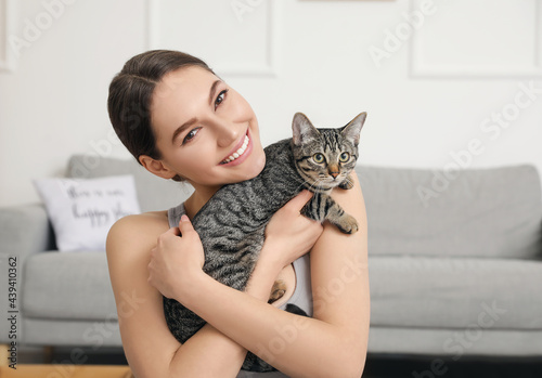 Beautiful young woman with cute cat at home