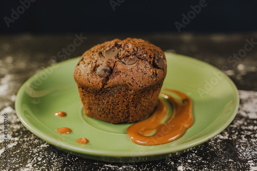 Homemade chocolate chips muffin with caramel on a green dish served gourmet