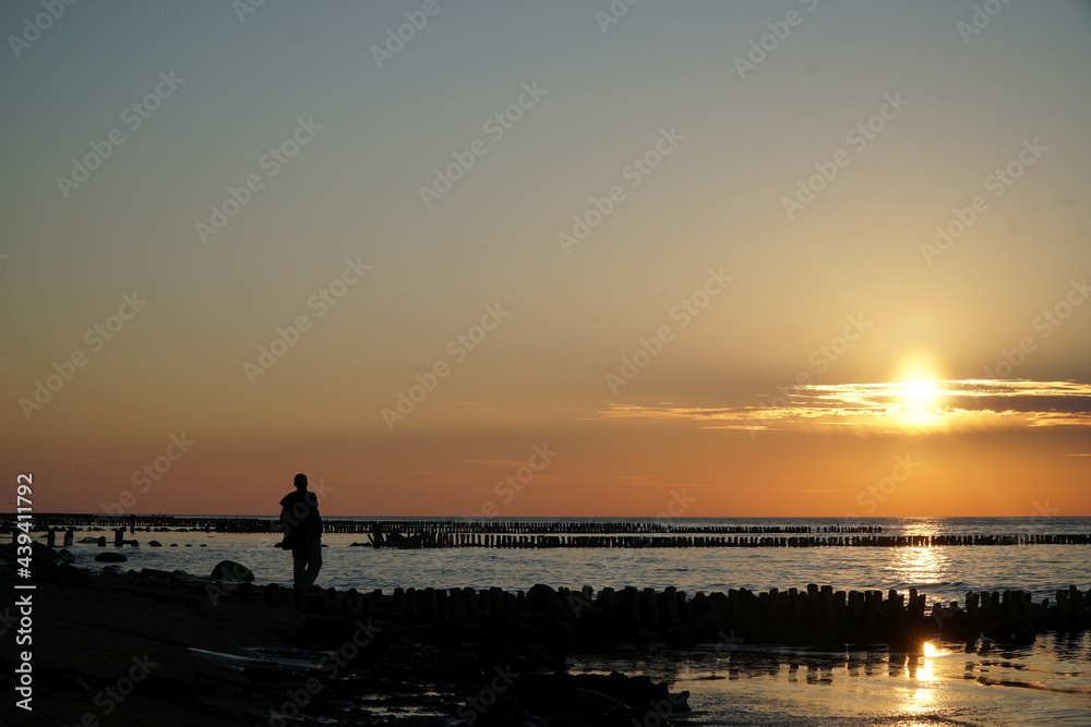 Sunset on the sea/ man staying in the calm water of the sea.