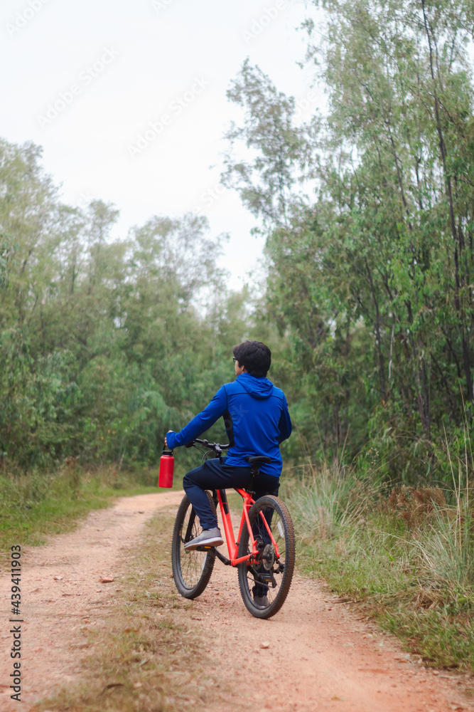 Young man on his bike on a forest road, playing sports in nature.