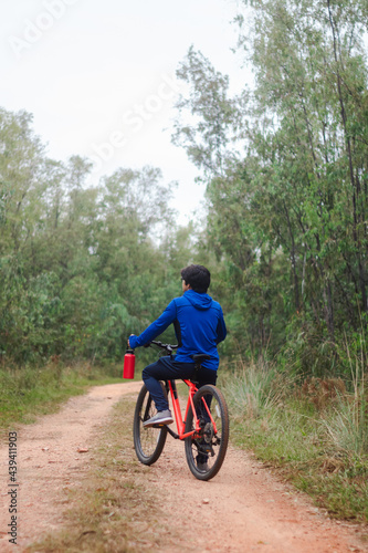 Young man on his bike on a forest road, playing sports in nature.