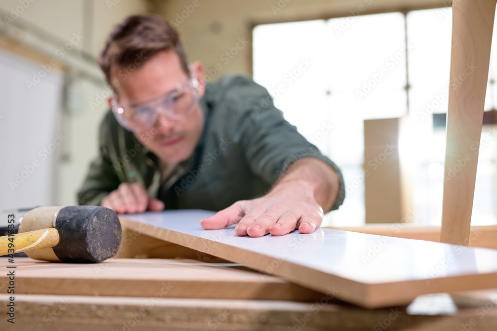 carpenter inspecting work after treating wood with protection paint and polishing. carpentry, hard at work, quality control, home improvement, do-it-yourself concept. focus on hands and board carpenter inspecting work after treating wood with protection paint and polishing. carpentry, hard at work, quality control, home improvement, do-it-yourself concept. focus on hands and board
