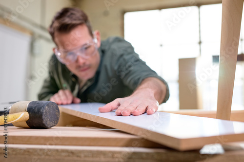 carpenter inspecting work after treating wood with protection paint and polishing. carpentry, hard at work, quality control, home improvement, do-it-yourself concept. focus on hands and board