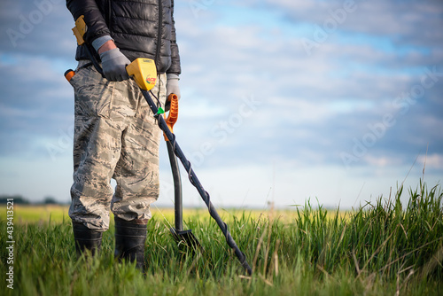 Man with a metal detector and shovel is searching the treasure concept.