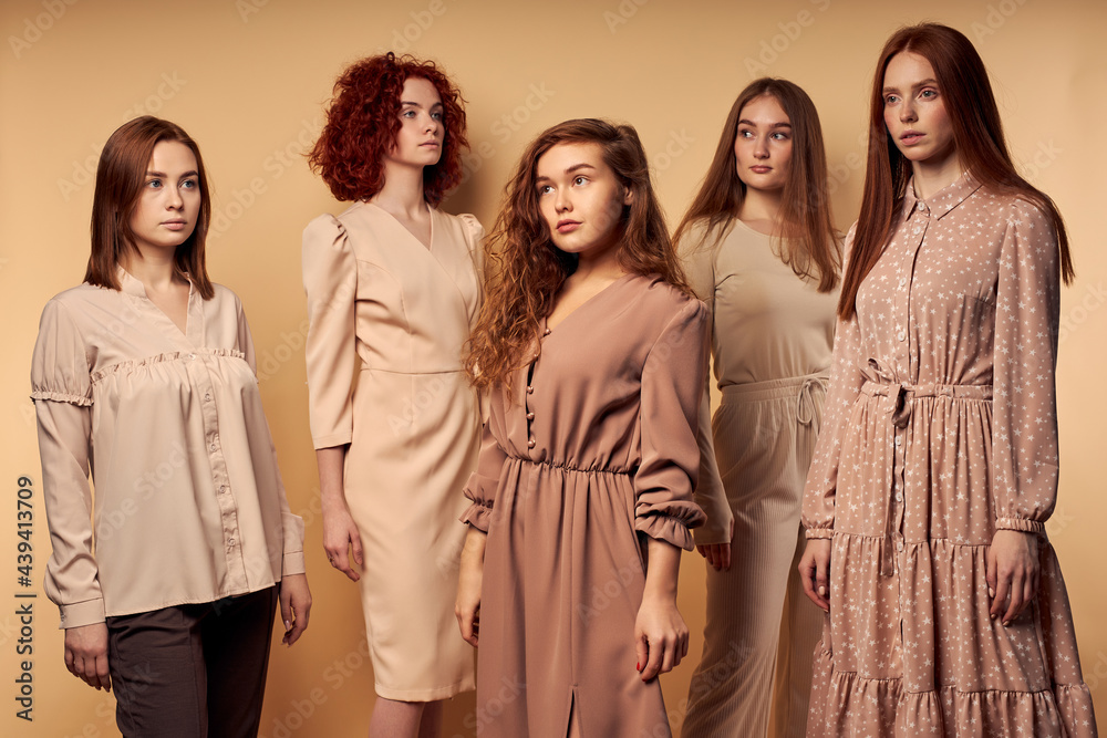 Group of redhead confident women in elegant stylish dresses posing at camera confidently, caucasian beautiful and fashionable ladies looking at side. Isolated on beige studio background, portrait Group of redhead confident women in elegant stylish dresses posing at camera confidently, caucasian beautiful and fashionable ladies looking at side. Isolated on beige studio background, portrait