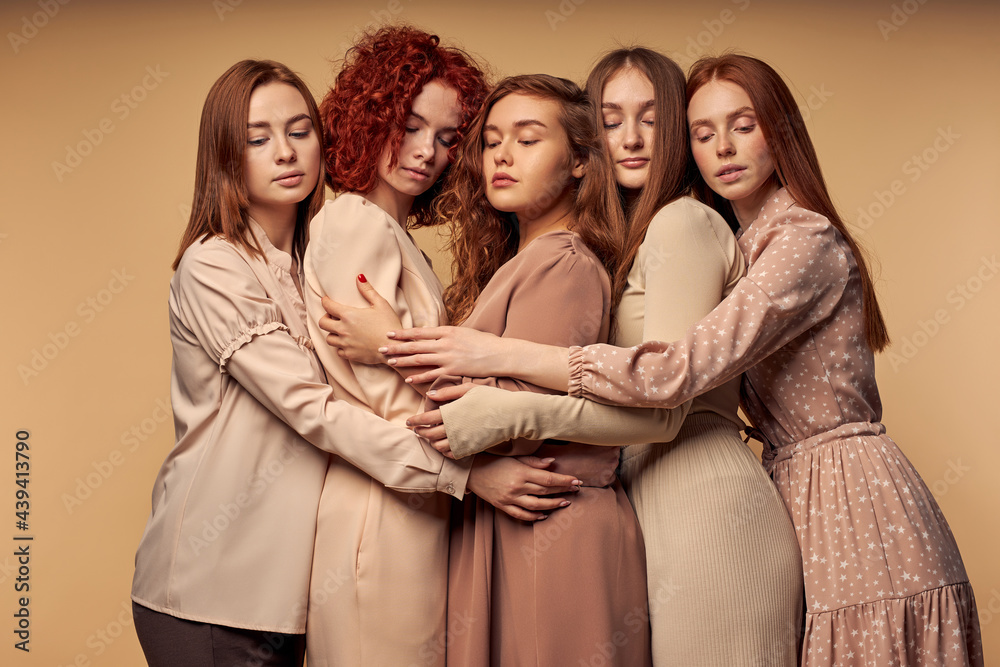 group of redhead models with natural beauty posing at camera together,hugging, feeling love, support and close friendship, wearing elegant dress. bewitching beauty of people with unusual hair colour