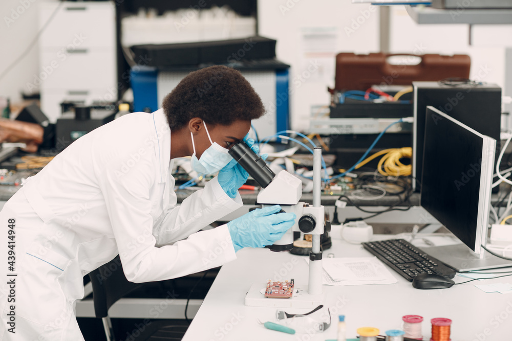 Scientist african american woman engineer working in laboratory with electronic tech instruments and microscope. Research and development of electronic devices by black woman. Scientist african american woman engineer working in laboratory with electronic tech instruments and microscope. Research and development of electronic devices by black woman.