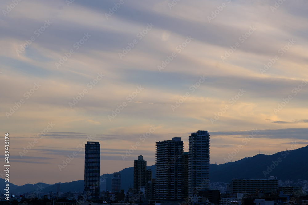 日の入り前の六甲山。西の空と雲がオレンジ色に染まるマジックアワー。高層ビルがシルエットで浮かぶ。１日の終わり。