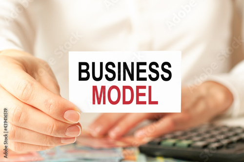 a woman in a white shirt holds a piece of paper with the text: business model, business concept.