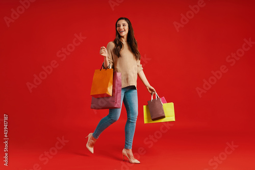 Full length of beautiful young woman in casual clothing carrying shopping bags photo