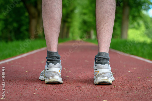 Runner feet standing on the running track in the park. 