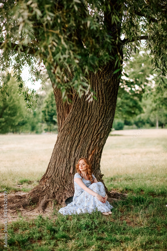 beautiful girl summer dress sits tree park