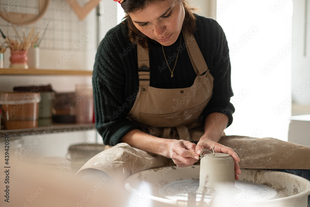 © Malquerida Studio/Stocksy - Ceramist young woman Making Clay vase With Pottery lathe in her studio