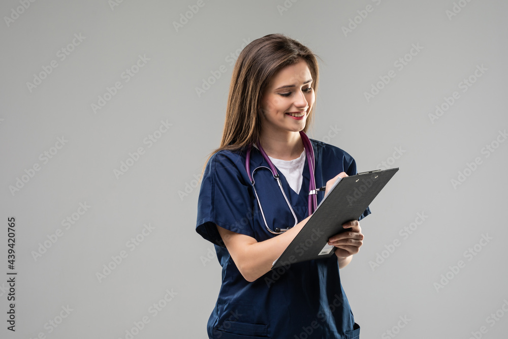 Photo of serious doctor hold clipboard pen write wear stethoscope specs white uniform isolated grey color background Photo of serious doctor hold clipboard pen write wear stethoscope specs white uniform isolated grey color background